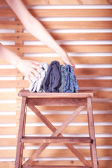 women's hands folded pile of clothes lying on a wooden chair on a wooden background