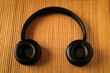 Black wireless headphones. Overhead, isolated professional-grade headphones. View from above.On a wooden background.