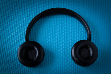 Black wireless headphones. Overhead, isolated professional-grade headphones. View from above. On a blue background.
