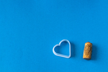 white heart and wine cork, on a blue background with a picture of grapes