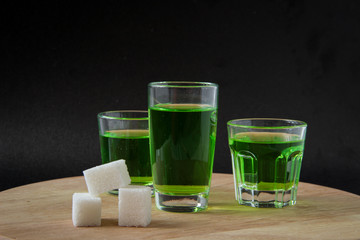 Strong alcohol. three shot glasses with absinthe, white sugar. on a black background