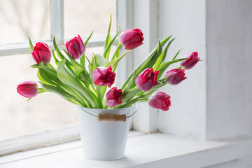 red tulips on old white windowsill