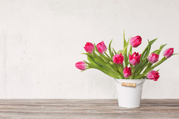 red tulips in bucket on background  old  white wall