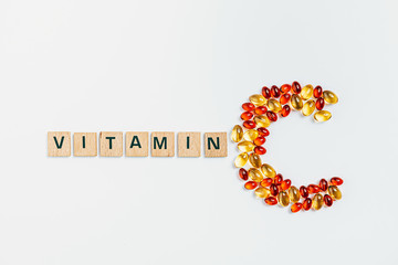 letter C made from transparent pills near the inscription Vitamin on a white background