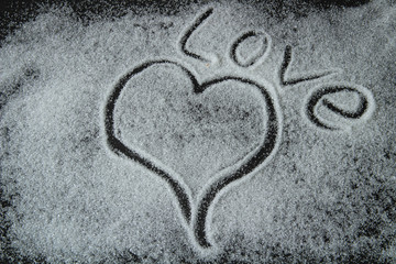 heart and the word love are drawn by sugar, on a black background, Valentine's Day