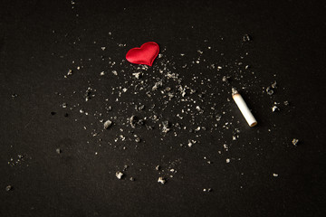 Smoking.tobacco cigarette butt . red heart on a black background