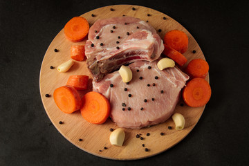 raw meat, steaks with chopped carrots and garlic, with pepper on a wooden board