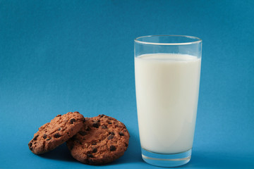 glass of milk with oatmeal cookies, on a blue background