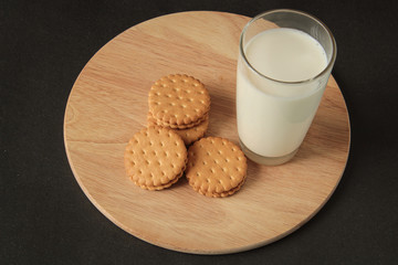 cookies and a glass with milk. cookies with cream, on a wooden board. Black background