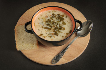 milk soup, on a wooden board with bread and a spoon, on a black background