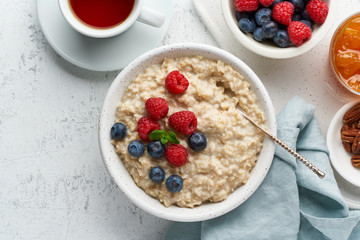 Oatmeal porridge with blueberry, raspberries, jam, copy space, top view. Breakfast with berries