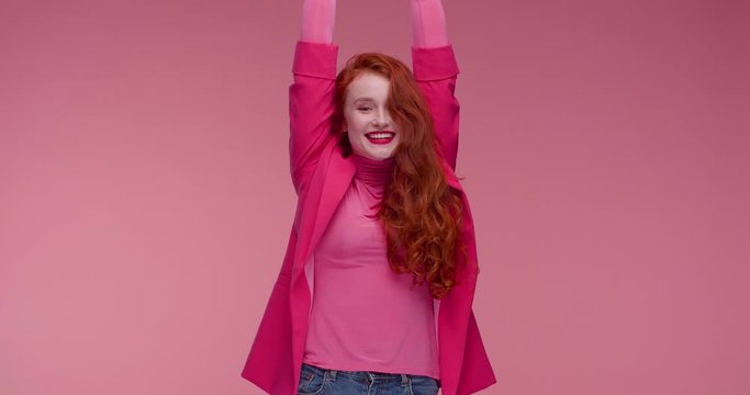 Attractive woman with Charming Smile making Sign of Happiness with her Hands. Putting hands Up, looking Satisfied. Successful woman. Wearing stylish pink suit and Having nice Hairstyle.