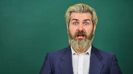 Teaching for surprise. Surprised teacher at green chalkboard. Bearded man keep mouth opened of surprise. School and education. Bringing surprise element into lesson. Surprise concept, copy space