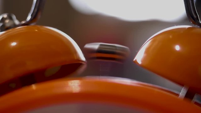 Close up of retro alarm clock going off on blurred background. Stock fooatge. Orange alarm clock details for waking up in the morning.