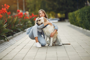 Fototapeta premium Beautiful girl in a park. Stylish girl in a jeans jacket. Lady with a dog