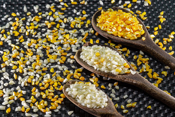 Wooden spoons with white and yellow hominy corn on black background
