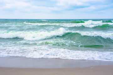 waves crash on sandy beach. cloudy weather before storm on the sea