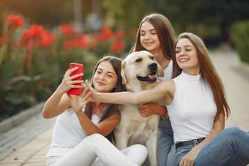 Beautiful girls sitting on the street. Women in a spring city. Ladies with cute dog.