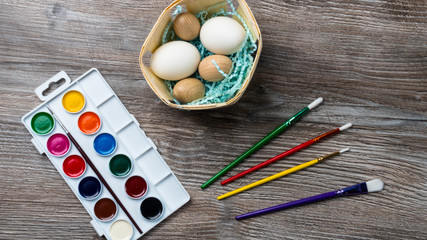 easter eggs in nest and colorful paints and brushes