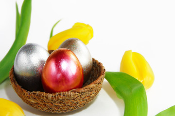 festive easter shiny eggs and yellow tulips flowers on a white background