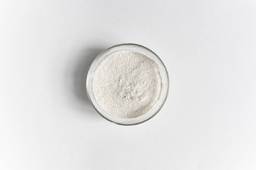 Powder of green buckwheat in glass bowl on white background