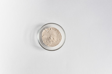 spelt grain powder in glass bowl on white background