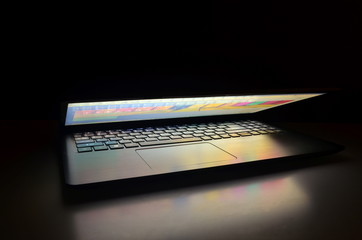 Semi opened Laptop with lighting, dark background 