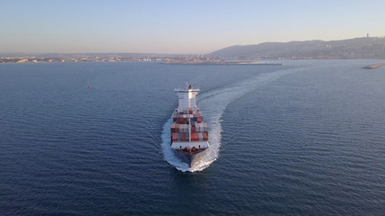 Aerial shot of container ship in ocean. Loaded vessel moves at calm water.