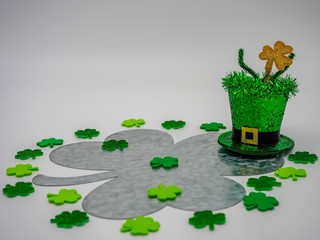 Leprechaun hat with a on top of a large rustic metal four leaf clover with lots of smaller green...
