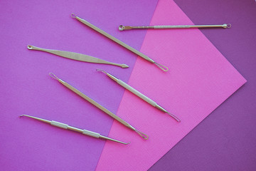 Tools for removing acne. Tools of the cosmetologist for problem skin on pink paper background.