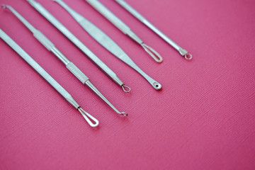 Tools for removing acne. Tools of the cosmetologist for problem skin on pink paper background.
