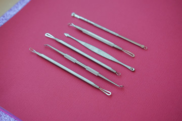 Tools for removing acne. Tools of the cosmetologist for problem skin on pink paper background.