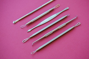 Tools for removing acne. Tools of the cosmetologist for problem skin on pink paper background.