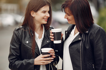 Beautiful girls in a summer city. Ladies with shopping bags. Mother with daughter drinking a coffee.