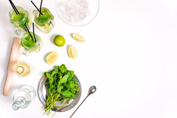 Three glass cocktail jars with a summer mojito alcoholic drink. Cooking Mojito. Ingredients for a summer cocktail on a table with copy space.