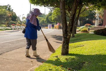 A woman worker sweeping leaves in the public park
