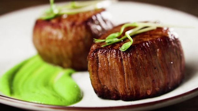 Filet mignon steak with mashed green peas and green pea sprouts.