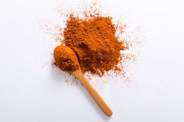 Top view of wooden spoon and red hot pepper powder on the white surface