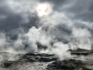 volcanic hotspring with steam under the sun