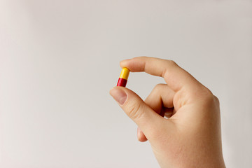 yellow and red medical capsule in human hand. Medicine treatment of diseases