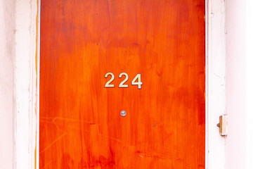 House number 224 on a varnished wooden front door