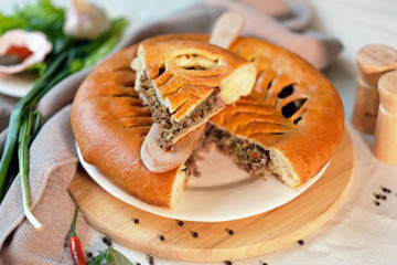 Round closed homemade baked pie with meat and cabbage.