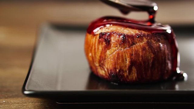 Chef pours filet mignon steak with pomegranate sauce.