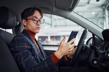 Fototapeta na wymiar Man in eyewear and formal clothes sitting inside of modern car