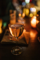 A glass of cocktail with truffle oil drops sitting on top of a table. Beautiful background with smooth bokeh