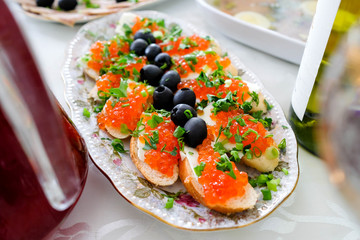 Appetizer with bread, butter and red caviar. Sandwiches with caviar, decorated with olives and green onions. A dish on the table for a celebration