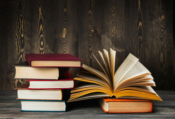 Open book with yellow pages on a wooden background copy space. Old textbook. A stack of books.
