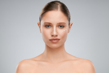 Beautiful caucasian brunette posing in studio with creme on face while looking at camera.
