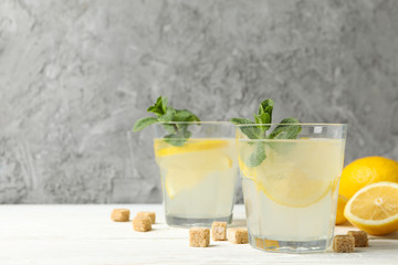 Lemonade, lemons and sugar cubes on wooden background, space for text