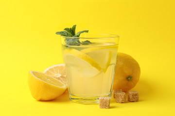 Lemonade, lemons and sugar cubes on yellow background, close up